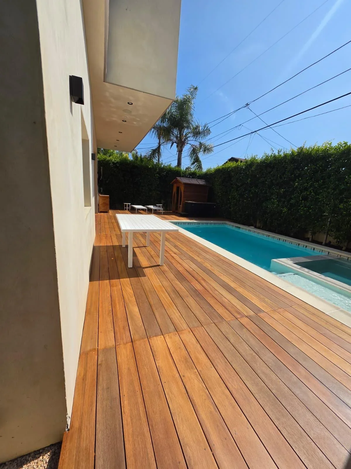 Wooden poolside deck with white pergola and turquoise pool in Cape Coral