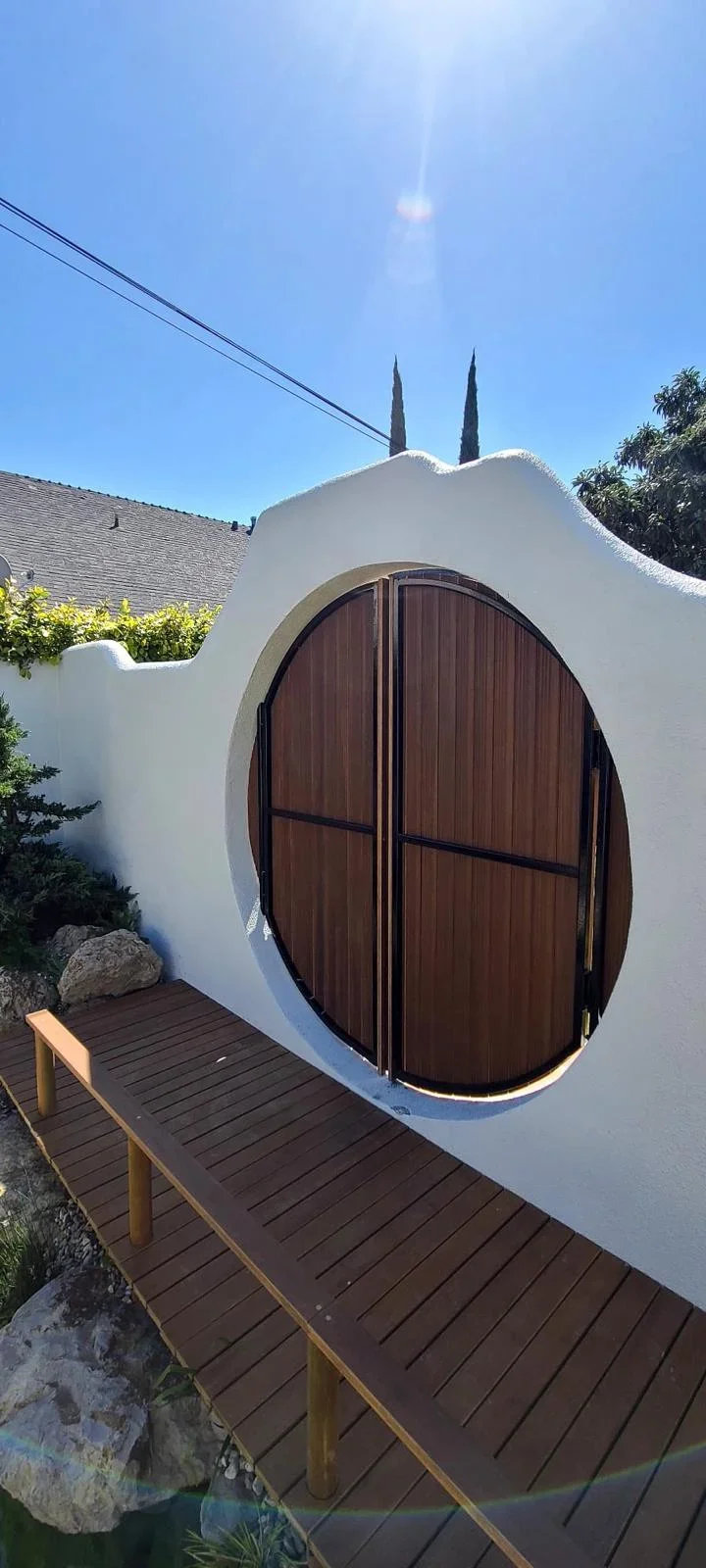 Modern curved composite deck with arched wooden door entry and integrated landscaping