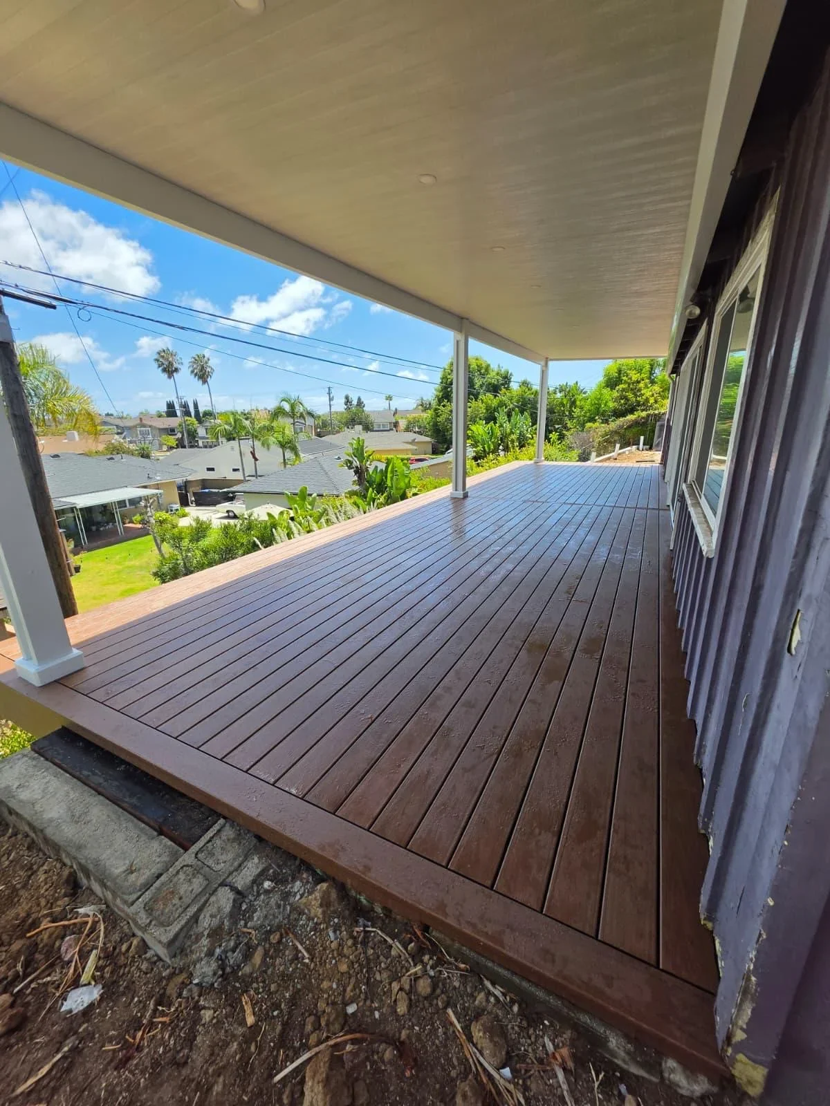 Dark composite deck with linear board pattern under covered patio structure overlooking Cape Coral neighborhood