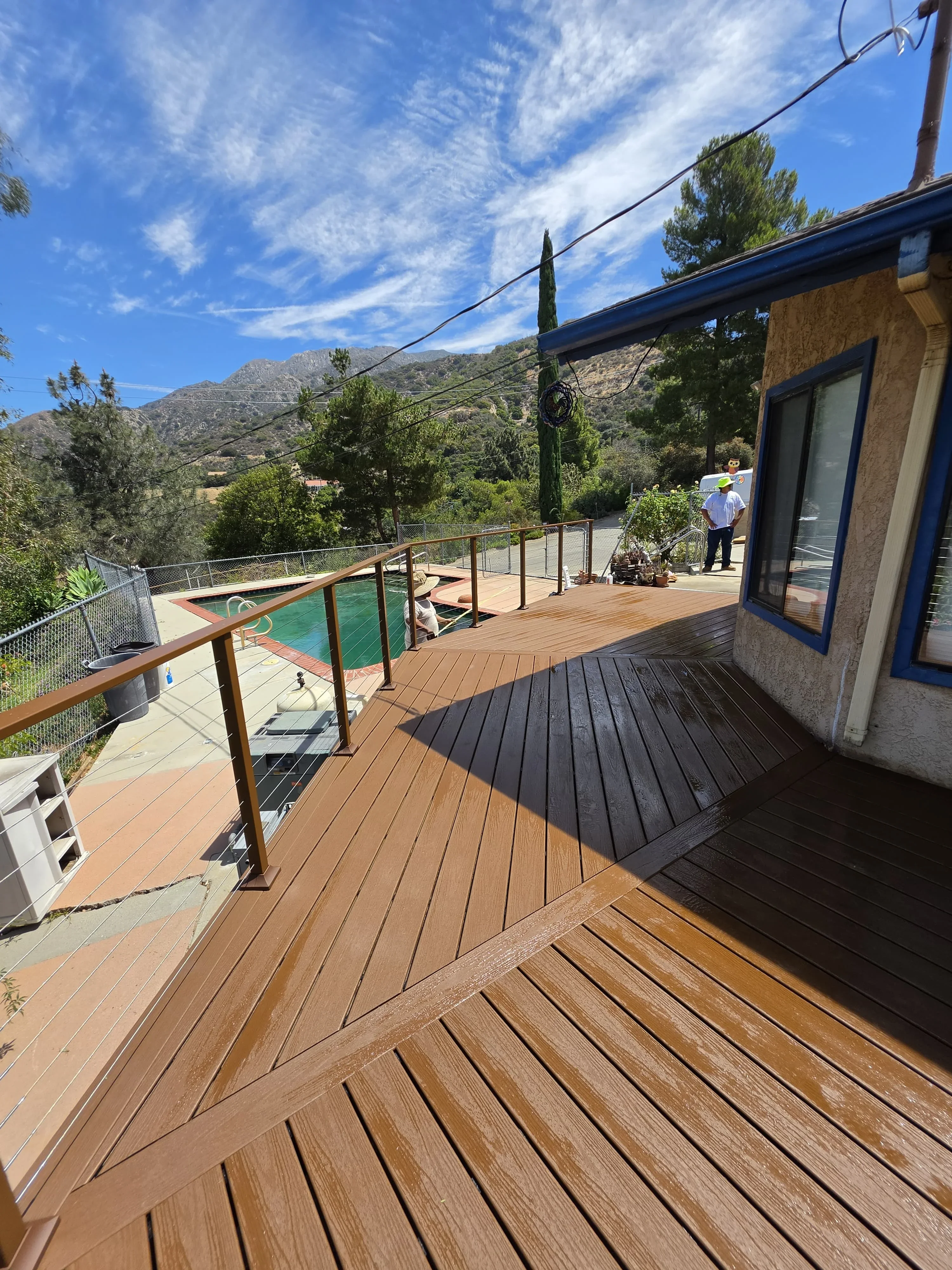 Multi-level composite deck with cable railing overlooking pool and mountain landscape