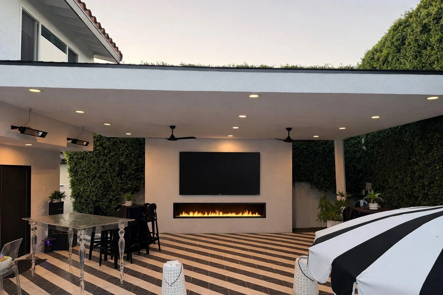 Modern covered patio with striped decking, fireplace, and green living walls